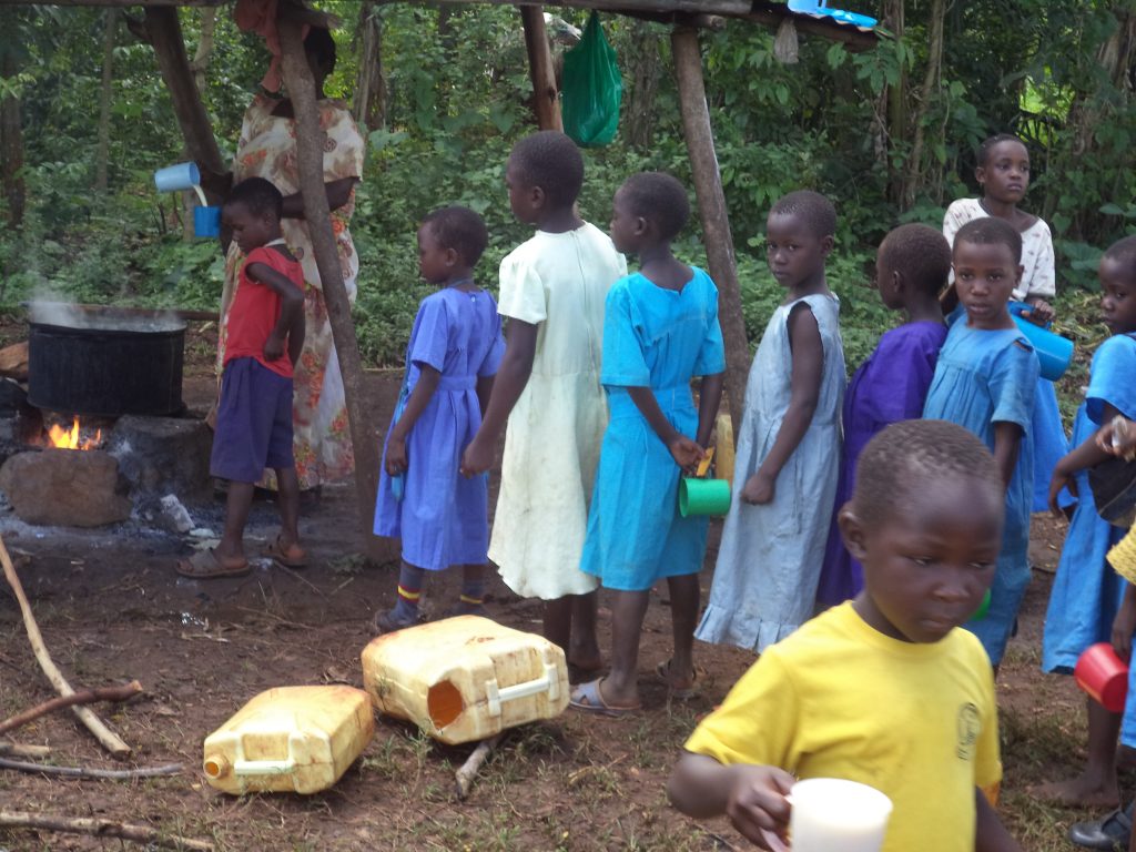 School kids line up to receive a cup of porridge for breakfast